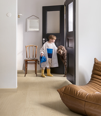 un bambino e un cano che entrano in un soggiorno con pavimento vinilico beige